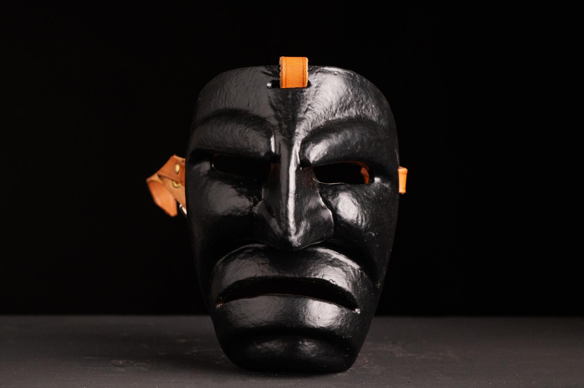 Maschera nera tradizionale fotografata su fondo scuro